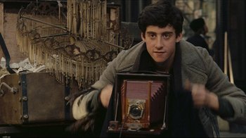 Movie still from “Once Upon a Time in America” (1984), directed by Sergio Leone – A man holding an old camera in front of an antique chandelier; Close Up shot, Over the shoulder angle