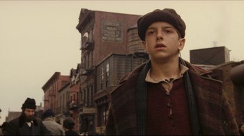 Movie still from “Once Upon a Time in America” (1984), directed by Sergio Leone – A young man standing in front of a row of brick buildings; Close Up shot, Low angle