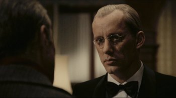 A man in a tuxedo looking at himself in the mirror