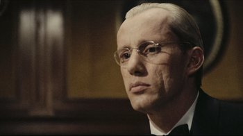 Movie still from “Once Upon a Time in America” (1984), directed by Sergio Leone – A man with a bald head wearing glasses and a suit; Close Up shot, Low angle