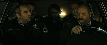 Movie still from “Once Upon a Time in Anatolia” (2011), directed by Nuri Bilge Ceylan – A man is being arrested by two police officers; Medium shot, Low angle