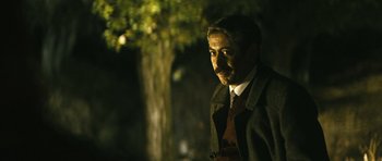 Movie still from “Once Upon a Time in Anatolia” (2011), directed by Nuri Bilge Ceylan – A man with a beard wearing a coat and tie; Medium shot, Over the shoulder angle