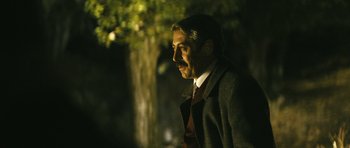 Movie still from “Once Upon a Time in Anatolia” (2011), directed by Nuri Bilge Ceylan – A man in a suit standing in front of a tree at night; Close Up shot, Over the shoulder angle