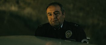 Movie still from “Once Upon a Time in Anatolia” (2011), directed by Nuri Bilge Ceylan – A man in a police uniform sitting in a car; Close Up shot, Low angle