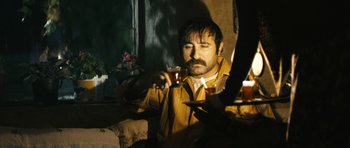 Movie still from “Once Upon a Time in Anatolia” (2011), directed by Nuri Bilge Ceylan – A man sitting in front of a window holding a glass of wine; Medium shot, Low angle