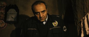 Movie still from “Once Upon a Time in Anatolia” (2011), directed by Nuri Bilge Ceylan – A man in a police uniform is looking at the camera; Close Up shot, Low angle