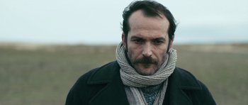 Movie still from “Once Upon a Time in Anatolia” (2011), directed by Nuri Bilge Ceylan – A man wearing a scarf and a jacket; Close Up shot, Low angle