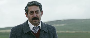Movie still from “Once Upon a Time in Anatolia” (2011), directed by Nuri Bilge Ceylan – A person wearing a suit and tie; Close Up shot, Over the shoulder angle