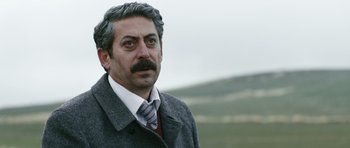 Movie still from “Once Upon a Time in Anatolia” (2011), directed by Nuri Bilge Ceylan – A person wearing a suit and tie; Close Up shot, Over the shoulder angle