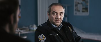 Movie still from “Once Upon a Time in Anatolia” (2011), directed by Nuri Bilge Ceylan – A man in a police uniform is looking at the camera; Medium shot, Over the shoulder angle