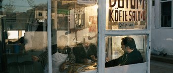 Movie still from “Once Upon a Time in Anatolia” (2011), directed by Nuri Bilge Ceylan – Two people sitting at a table in a restaurant; Wide shot, Low angle