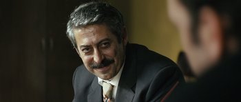 Movie still from “Once Upon a Time in Anatolia” (2011), directed by Nuri Bilge Ceylan – A person wearing a suit and tie; Close Up shot, Over the shoulder angle
