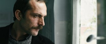 Movie still from “Once Upon a Time in Anatolia” (2011), directed by Nuri Bilge Ceylan – A person wearing a suit and tie; Close Up shot, Low angle