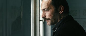 Movie still from “Once Upon a Time in Anatolia” (2011), directed by Nuri Bilge Ceylan – A person smoking a cigarette near a window; Close Up shot, Low angle