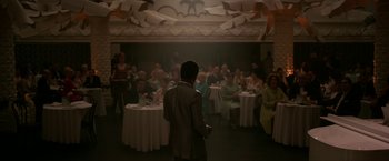 Movie still from “One Night in Miami...” (2020), directed by Regina King – A man standing in front of a crowd of people in a room; Wide shot, High angle