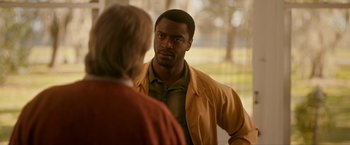 Movie still from “One Night in Miami...” (2020), directed by Regina King – A man in a yellow jacket talking to a woman in an orange jacket; Medium shot, Over the shoulder angle