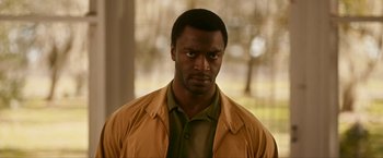 Movie still from “One Night in Miami...” (2020), directed by Regina King – A man in a brown jacket looking at the camera; Close Up shot, Over the shoulder angle