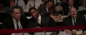 Movie still from “One Night in Miami...” (2020), directed by Regina King – A man sitting at a table with a pencil in his hand; Medium shot, High angle