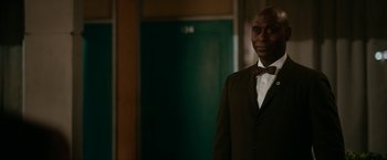 Movie still from “One Night in Miami...” (2020), directed by Regina King – A man in a suit and bow tie standing in front of an elevator; Close Up shot, Over the shoulder angle