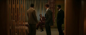 Movie still from “One Night in Miami...” (2020), directed by Regina King – A group of men standing around a man in a suit; Wide shot, Over the shoulder angle