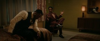 Movie still from “One Night in Miami...” (2020), directed by Regina King – A man in a suit and tie sitting on a chair in front of another man in a suit and tie; Medium shot, Over the shoulder angle