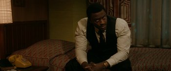 Movie still from “One Night in Miami...” (2020), directed by Regina King – A man sitting on top of a couch in a room; Medium shot, High angle