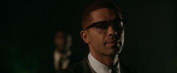 Movie still from “One Night in Miami...” (2020), directed by Regina King – A person wearing glasses and a suit; Close Up shot, Over the shoulder angle