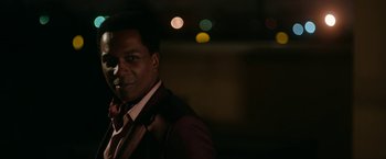 Movie still from “One Night in Miami...” (2020), directed by Regina King – A man wearing a suit and tie standing in the dark; Close Up shot, Over the shoulder angle