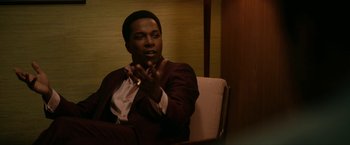 Movie still from “One Night in Miami...” (2020), directed by Regina King – A man sitting in a chair with his hands in the air; Medium shot, Over the shoulder angle