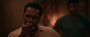 Movie still from “One Night in Miami...” (2020), directed by Regina King – A man is smoking a cigarette while sitting in a room; Close Up shot, Over the shoulder angle
