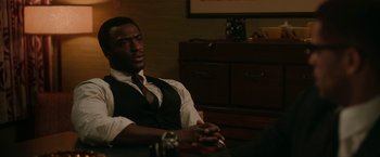 Movie still from “One Night in Miami...” (2020), directed by Regina King – A man sitting in front of a wooden desk; Medium shot, Over the shoulder angle