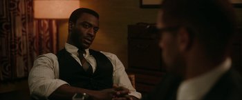 Movie still from “One Night in Miami...” (2020), directed by Regina King – A man in a vest and tie talking to another man; Medium shot, Over the shoulder angle