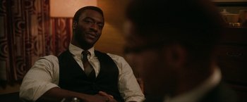 Movie still from “One Night in Miami...” (2020), directed by Regina King – A man in a vest and tie sitting in front of another man; Close Up shot, Over the shoulder angle