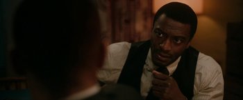 Movie still from “One Night in Miami...” (2020), directed by Regina King – A person wearing a suit and tie; Close Up shot, Over the shoulder angle