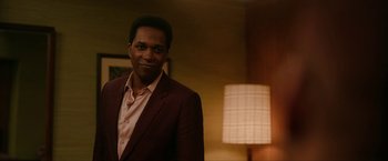 Movie still from “One Night in Miami...” (2020), directed by Regina King – A man standing in a room next to a lamp; Medium shot, Over the shoulder angle