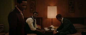 Movie still from “One Night in Miami...” (2020), directed by Regina King – A man sitting at a table in a room with another man; Medium shot, Over the shoulder angle