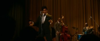 Movie still from “One Night in Miami...” (2020), directed by Regina King – A man in a suit and tie is on a stage with a microphone; Medium shot, Over the shoulder angle