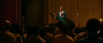 Movie still from “One Night in Miami...” (2020), directed by Regina King – A man in a green jacket is speaking to a crowd; Medium shot, Low angle