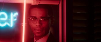Movie still from “One Night in Miami...” (2020), directed by Regina King – A person wearing a suit and glasses; Close Up shot, Over the shoulder angle