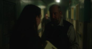 Movie still from “Orphan: First Kill” (2022), directed by William Brent Bell – A man and a woman are talking in a dark room; Medium shot, Over the shoulder angle