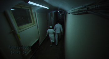 Movie still from “Orphan: First Kill” (2022), directed by William Brent Bell – A man and a woman walking down a long hallway; Wide shot, High angle