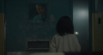 Movie still from “Orphan: First Kill” (2022), directed by William Brent Bell – A man is reflected in a mirror in a room with a girl; Medium shot, Over the shoulder angle