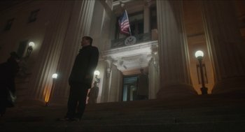 Movie still from “Orphan: First Kill” (2022), directed by William Brent Bell – A man standing in front of a large building; Wide shot, Low angle