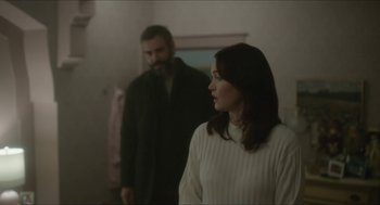 Movie still from “Orphan: First Kill” (2022), directed by William Brent Bell – A man and a woman standing next to each other in a room; Medium shot, Over the shoulder angle