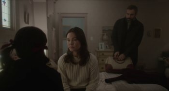 Movie still from “Orphan: First Kill” (2022), directed by William Brent Bell – A woman sitting on the floor in front of a man; Medium shot, Over the shoulder angle