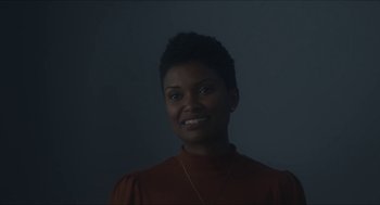 Movie still from “Orphan: First Kill” (2022), directed by William Brent Bell – A black woman with short black hair wearing a red shirt; Close Up shot, Low angle