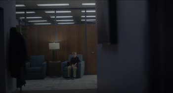 Movie still from “Orphan: First Kill” (2022), directed by William Brent Bell – A boy sitting on a chair in a room; Wide shot, Over the shoulder angle