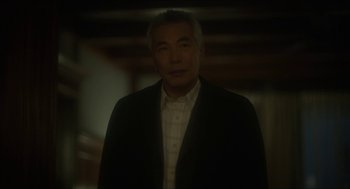 Movie still from “Orphan: First Kill” (2022), directed by William Brent Bell – A man in a black jacket and a white shirt; Close Up shot, Over the shoulder angle