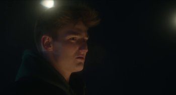Movie still from “Orphan: First Kill” (2022), directed by William Brent Bell – A man with a light on his head looking into the distance; Close Up shot, Low angle
