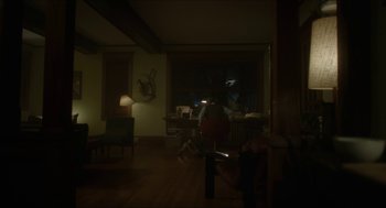 Movie still from “Orphan: First Kill” (2022), directed by William Brent Bell – A dark room with a person sitting at a desk; Extreme Wide shot, High angle